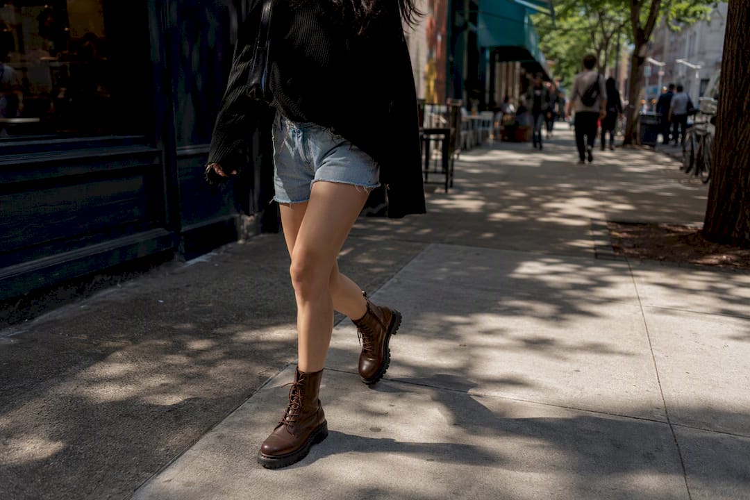 Person walking wearing brown combat boots and layered urban outfit